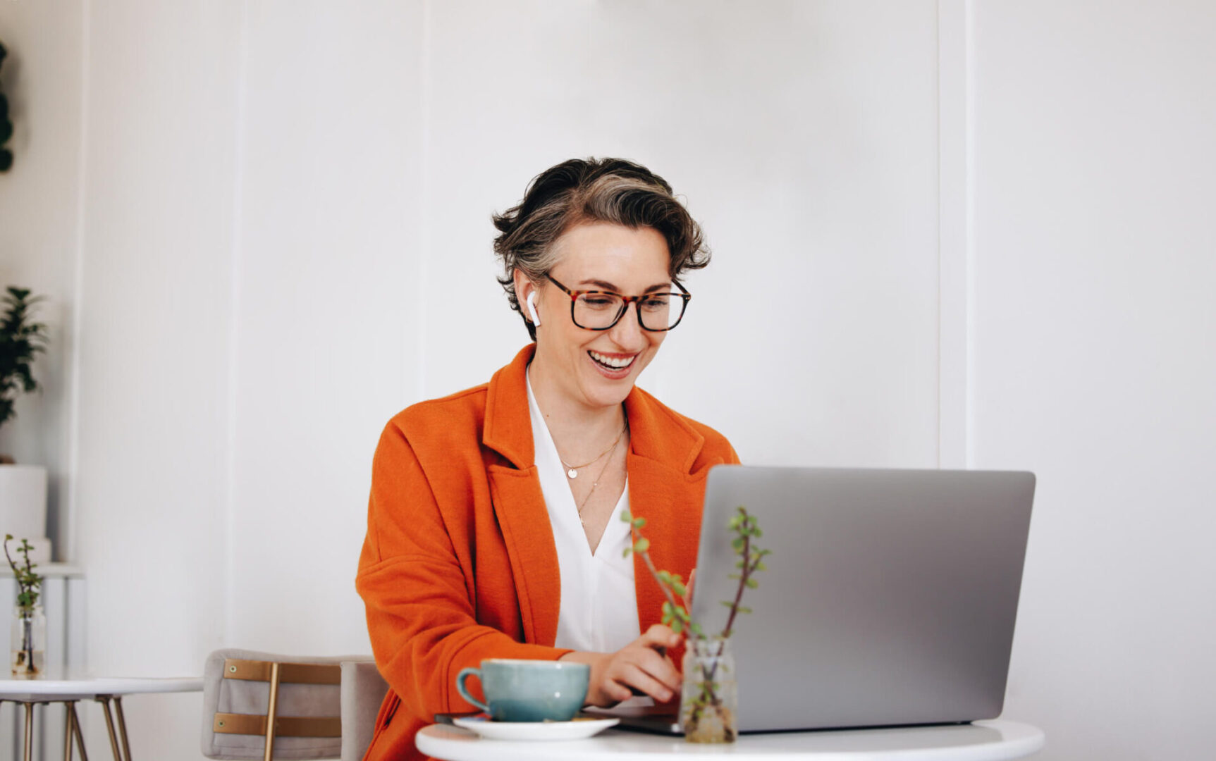 Smiling woman working on laptop in cafe.