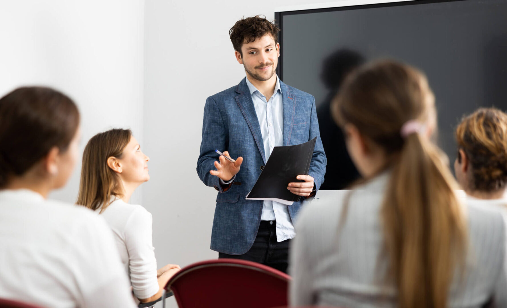 Man presenting to audience with notes.